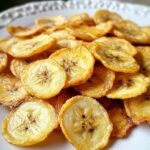 Air Fryer Banana Chips, a crispy golden pile of thinly sliced banana chips with a slight sheen from minimal oil