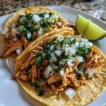 chicken street tacos, featuring two warm corn tortillas filled with shredded cumin-spiced chicken